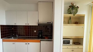 Une cuisine de taille réduite avec des meubles blancs, un plan de travail noir et un four à micro-ondes.