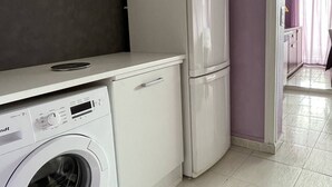 A compact kitchen with a washing machine, a refrigerator, and a microwave. - Apartment Héliopolis E 78 - 4 people (AGDE)