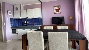 A compact living space with a kitchenette, dining area, and a TV. - Apartment Héliopolis E 78 - 4 people (AGDE)