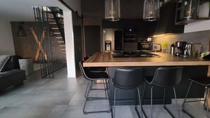 Een moderne keuken met een centraal eiland, barstoelen en een trap naar een ander niveau.