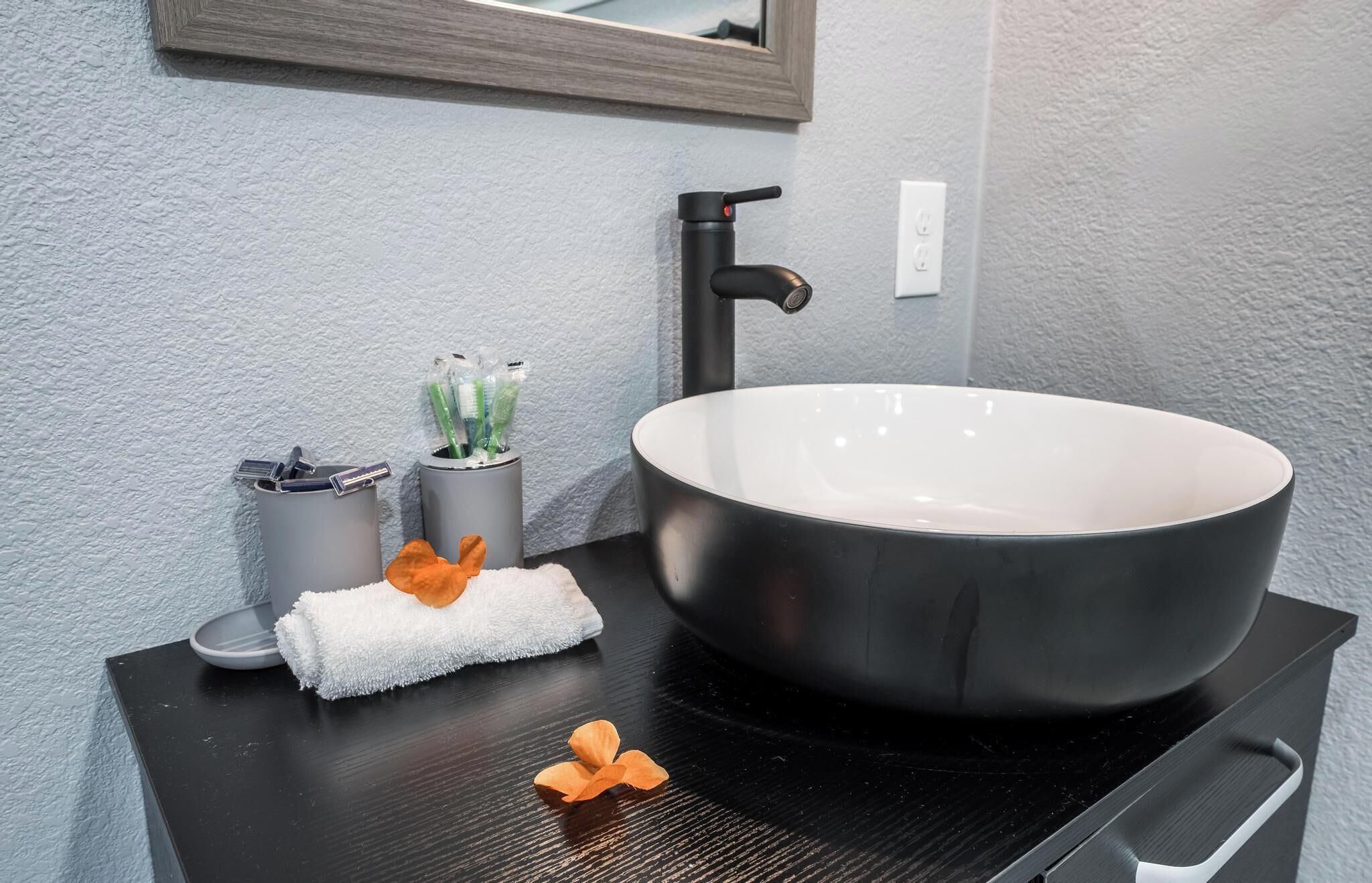 A modern bathroom with a large vessel sink, a towel, and toiletries.