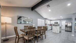 Une cuisine moderne avec des meubles blancs, un réfrigérateur en acier inoxydable et un îlot central en marbre.