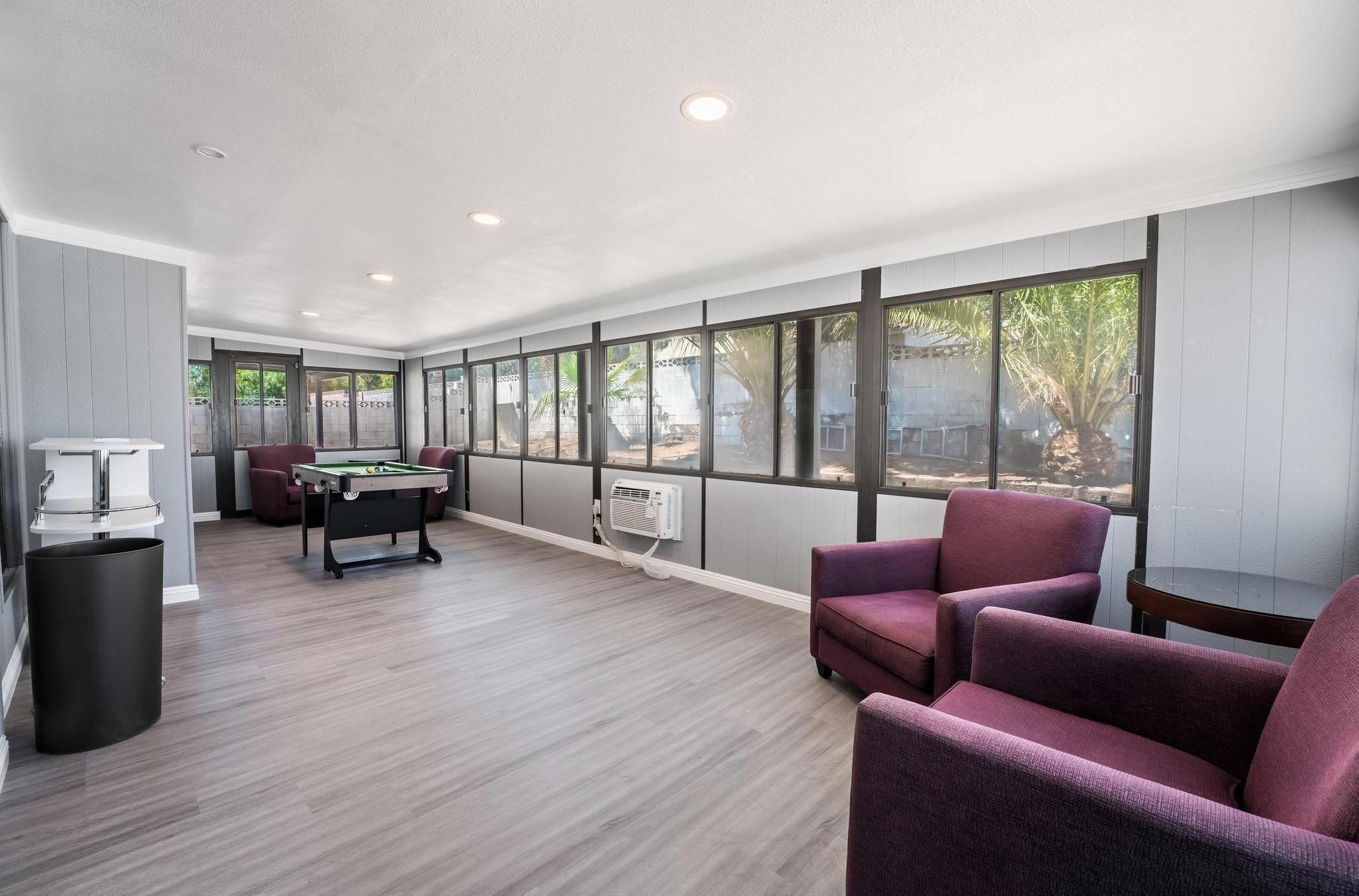 Una habitación amplia con mesa de billar, asientos cómodos y grandes ventanales con vistas al exterior.