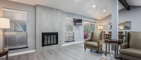 A spacious living room with a fireplace, comfortable seating, and a dining area.
