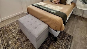 Une chambre à coucher avec un lit, une table de chevet, une lampe et une petite table ronde sur laquelle est posée une plante.