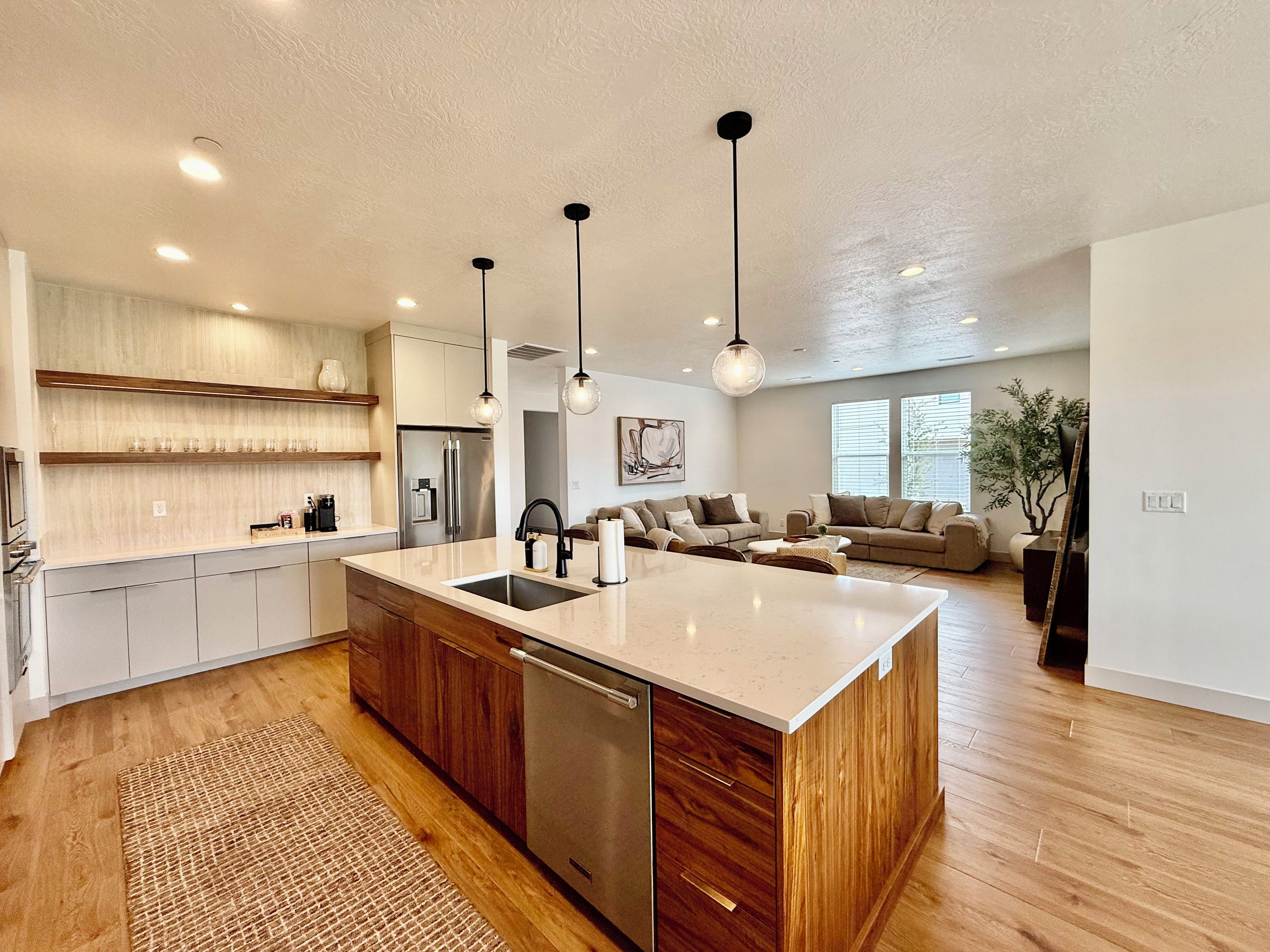 Una cocina moderna con una isla central, armarios de madera e iluminación colgante.