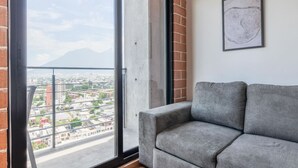 Ein Balkon mit Blick auf die Stadt, ein graues Sofa und eine gerahmte Karte an der Wand.