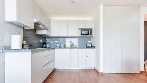 Eine moderne Küche mit weißen Schränken, einer Mikrowelle und einer Kaffeemaschine.