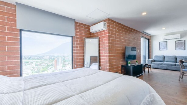 Ein modernes Hotelzimmer mit einem großen Bett, einem Schreibtisch, einem grauen Sofa und einem Fernseher.