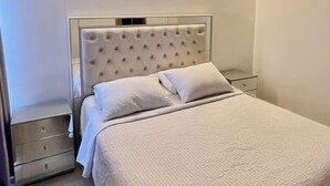 Ein modernes Schlafzimmer mit einer gesteppten Kopfteil, einem Einzelbett, einem Nachttisch und einem Beistelltisch.