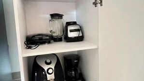 Eine Küchenschrank mit einem Mixer, einer Kaffeemaschine und einem Toaster auf den Regalen.