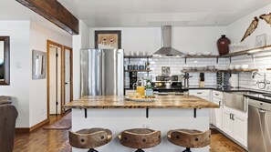 Una cocina moderna con una isla central, electrodomésticos de acero inoxidable y taburetes de madera.