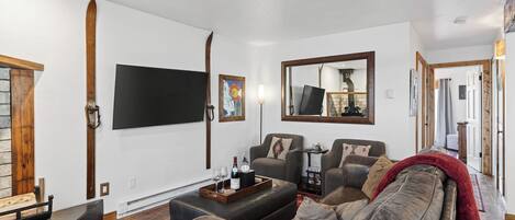 Un salon doté d’un grand téléviseur à écran plat, d’une cheminée, d’un canapé et d’une table basse.