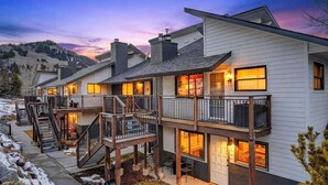 A multi-story residential building with a balcony, a staircase, and a view of the surrounding landscape.
