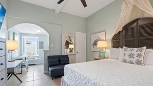 A bedroom with a large bed, a desk, and a chair. There is a door leading to another room. - Beachview 321 Studio across from the Hangout (Gulf Shores)