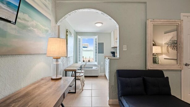 A room with a wooden table, a black sofa, a lamp, and a painting of a beach scene. - Beachview 321 Studio across from the Hangout (Gulf Shores)