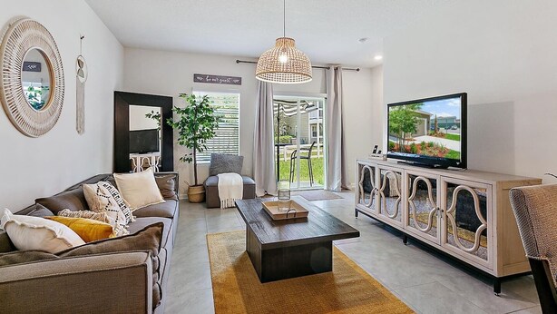 A modern living room with a sofa, coffee table, TV, and a large window. - Palm Villa: 5 beds Playground, UNF, Mayo, Downtown (Jacksonville)