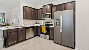 A modern kitchen with dark wood cabinets, stainless steel appliances, and a white countertop. - Palm Villa: 5 beds Playground, UNF, Mayo, Downtown (Jacksonville)