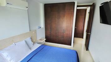 A bedroom with a bed, a wardrobe, a TV, and a small bedside table.