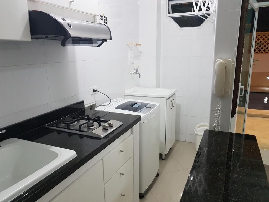 A compact kitchen with a gas stove, a built-in oven, a small sink, and a window above the sink.