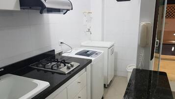 A compact kitchen with a gas stove, a built-in oven, a small sink, and a window above the sink.