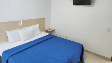 Un lit simple avec une tête de lit en bois, des oreillers blancs et une couverture bleue.