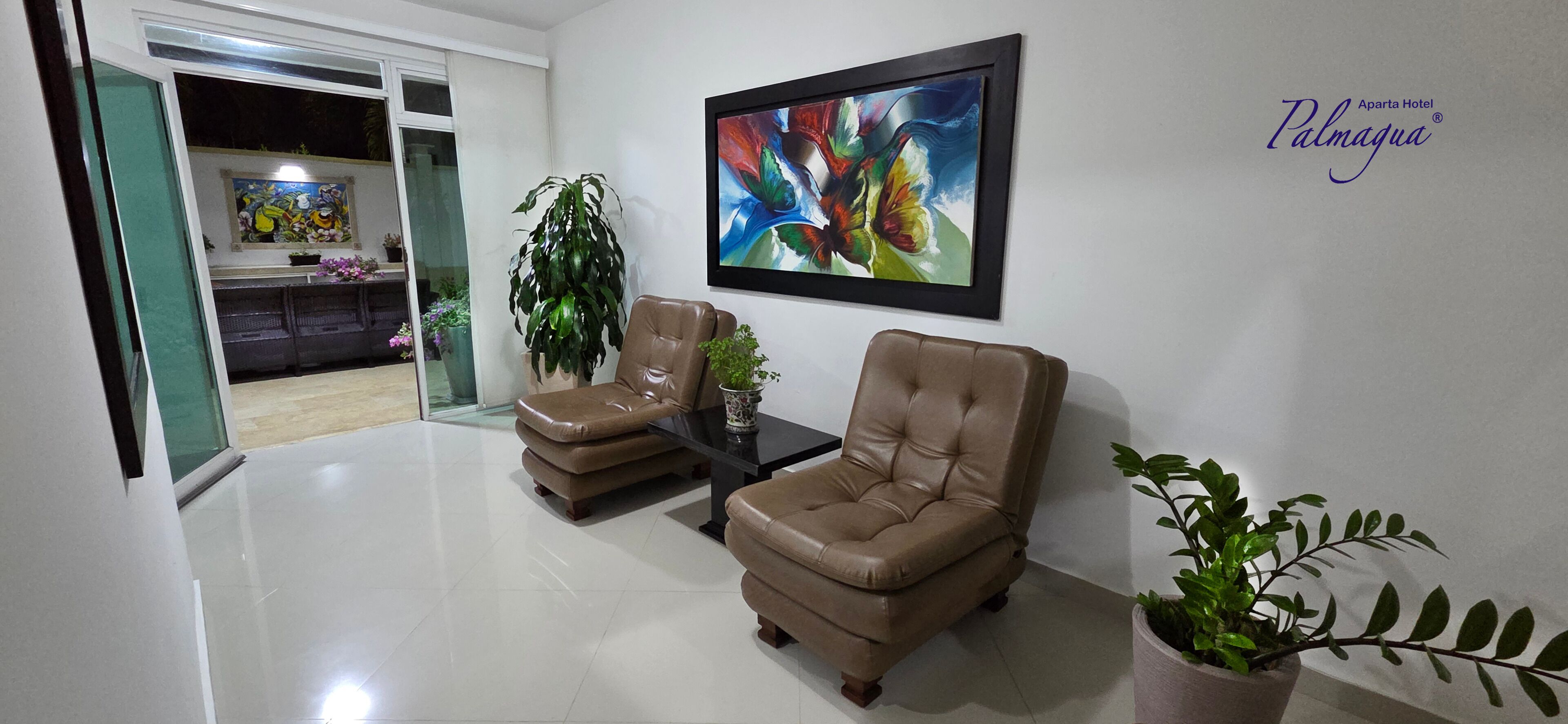 A modern living room with two leather armchairs, a glass coffee table, and a large abstract painting on the wall.
