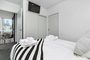 Ein Hotelzimmer mit Bett, Stuhl, Tisch und einem Balkon mit Blick auf die Stadt.