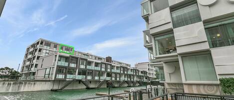 A modern building with a glass facade, a bridge over water, and a green highlighted area.