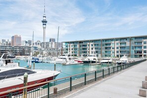 A marina with boats docked, a prominent tower in the background, and modern buildings with balconies. - Sophisticated 1 Bedroom Living with Parking (Auckland City)