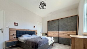 Un dormitorio moderno con cama, mesitas de noche, escritorio y armario.