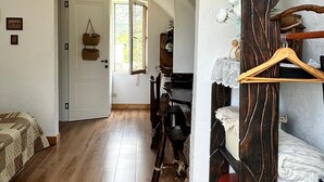 A spacious room with wooden flooring, a bed, a desk, and a wardrobe.