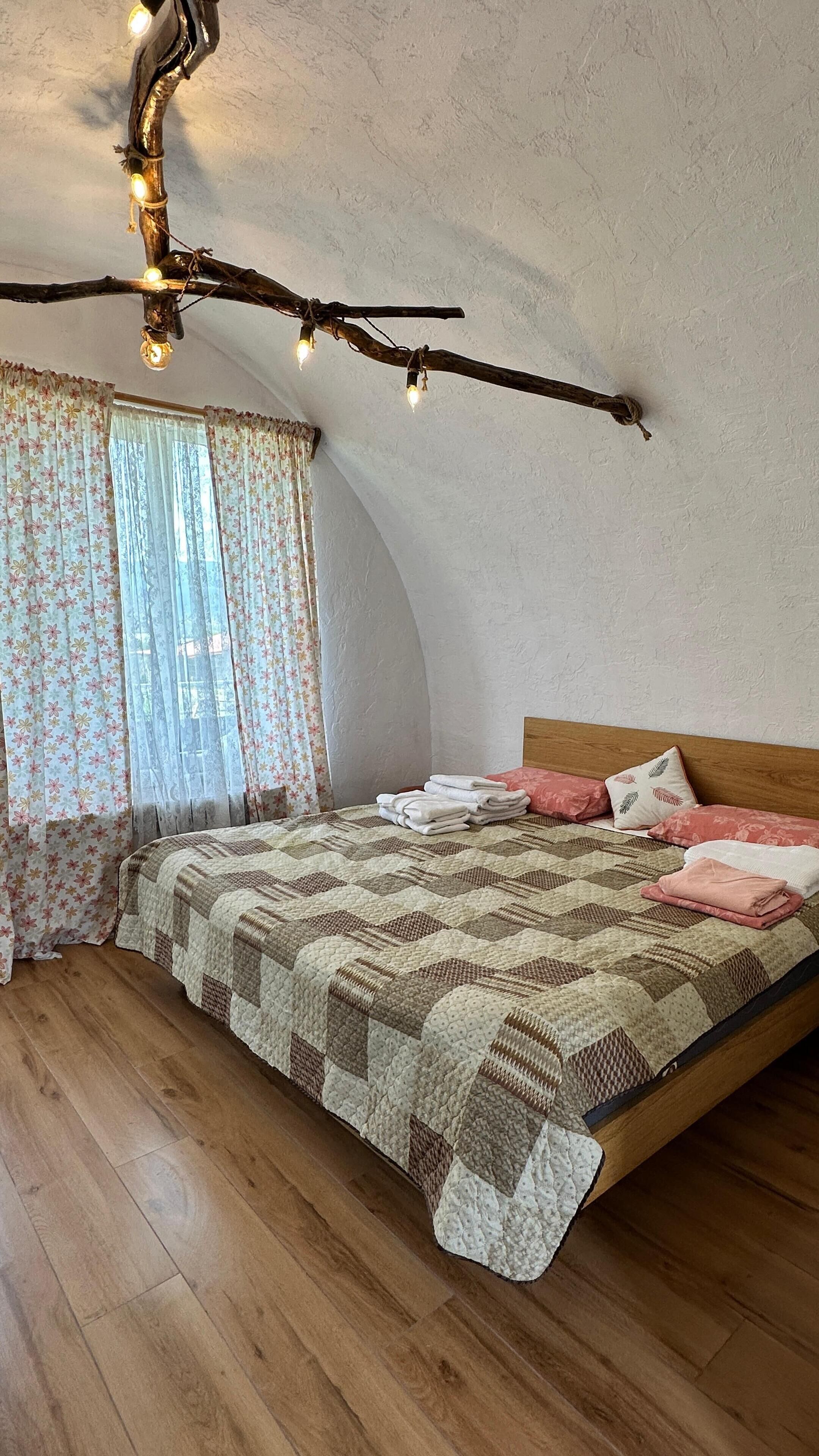 A bedroom with a wooden bed, floral curtains, and a branch light fixture.