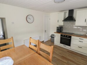 A compact kitchen with white cabinets, a built-in oven, and a coffee maker. - GREENFIELD HOUSE, family friendly in Aughavas, County Leitrim (Aughavas)