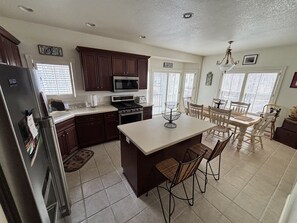 A kitchen with dark wooden cabinets, a stainless steel refrigerator, a microwave, an oven, and a dining area with a table and chairs. - Elkhart Lake Fun in the Sun (Elkhart Lake)