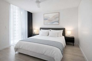 A modern hotel room with a large bed, two bedside tables with lamps, a ceiling fan, and a large window with curtains. - Brisbane CBD 2BR Gem w/ Skyline Views + Parking (Brisbane)