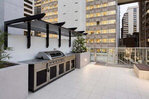 An outdoor kitchen with a grill, built-in cabinets, and a pergola structure. - Brisbane CBD 2BR Gem w/ Skyline Views + Parking (Brisbane)