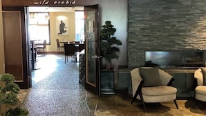 Un hall d’entrée avec un mur en pierre, un téléviseur et des espaces où l’on peut s’asseoir.