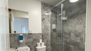 Un baño moderno con cabina de ducha de vidrio, lavabo pedestal y un inodoro.