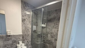 Un baño moderno con ducha envuelta en vidrio, inodoro y lavabo.