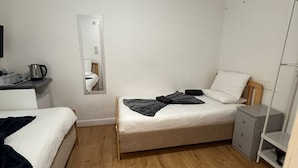 Una habitación pequeña y limpia con cama, mesita de noche, espejo y armario.