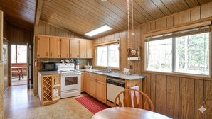 Cocina de cabaña de madera con estufa, microondas y alacenas de madera.