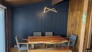 A wooden dining table with chairs, a neon light, and a blue wall.