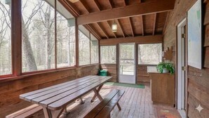 Una cabaña de madera con un ventanal grande, un banco y una puerta.