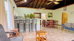 A spacious living area with a high ceiling, a dining table, and a sofa. - Posada de Paz 1: A Family Refuge at Corcovado (Provincia de Puntarenas)
