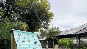 A swimming pool with a rock climbing wall and a tiled deck. - Posada de Paz 1: A Family Refuge at Corcovado (Provincia de Puntarenas)