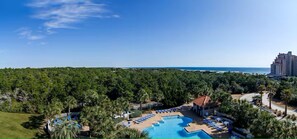 Un resort con piscina rodeada de palmeras y vista al océano.