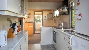 Una cocina con armarios blancos, un lavamanos, una cafetera y un refrigerador.