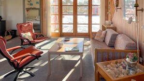 Una sala de estar acogedora con un sofá, dos sillones, una mesa baja y una mesa de vidrio decorada con objetos.