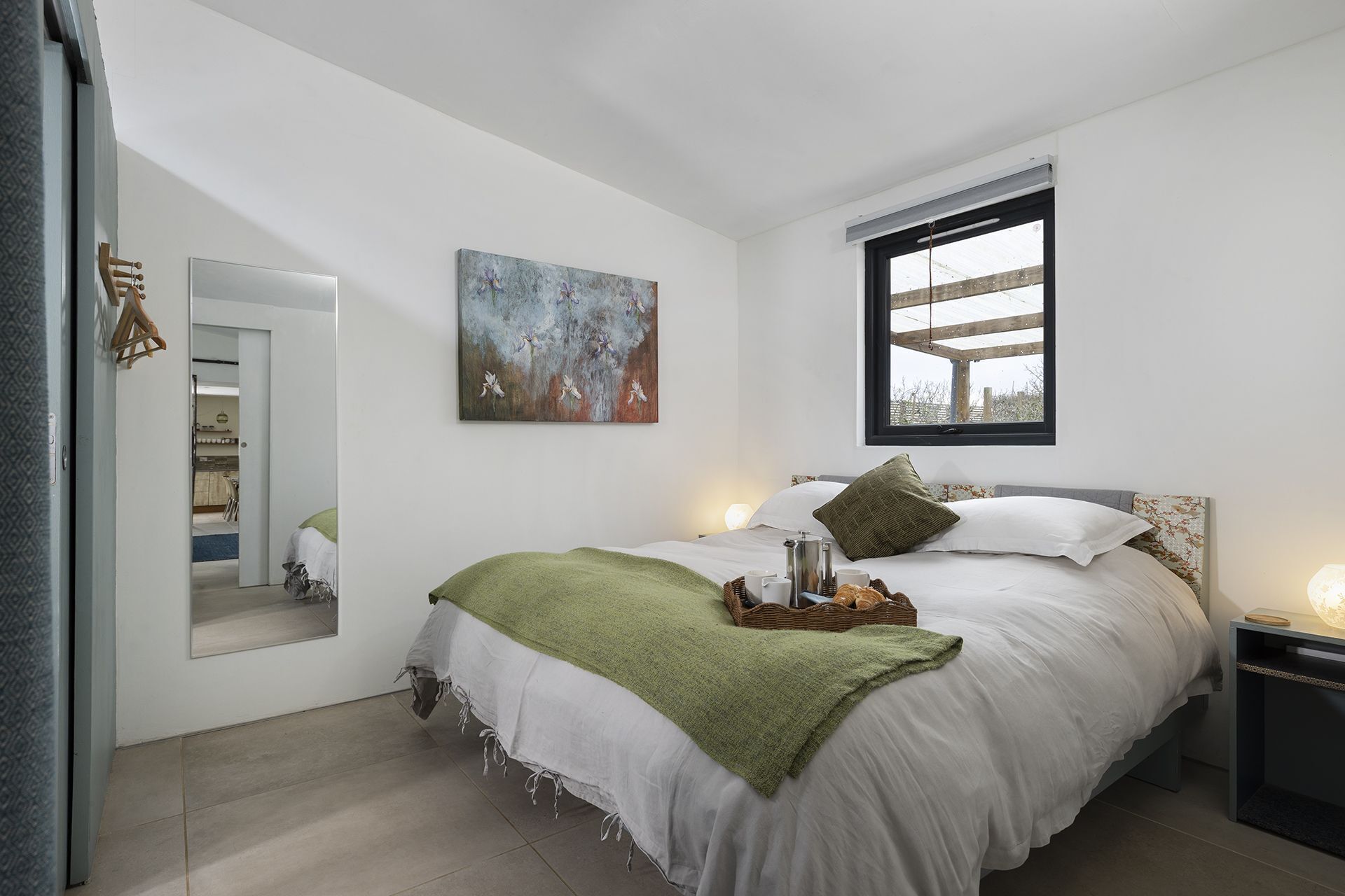 Une chambre moderne avec un grand lit, un tableau, une fenêtre et une table de chevet.
